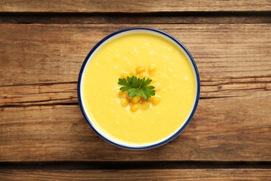 Photo of Delicious creamy corn soup on wooden table, top view