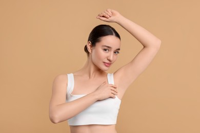 Beautiful woman showing armpit with smooth clean skin on beige background