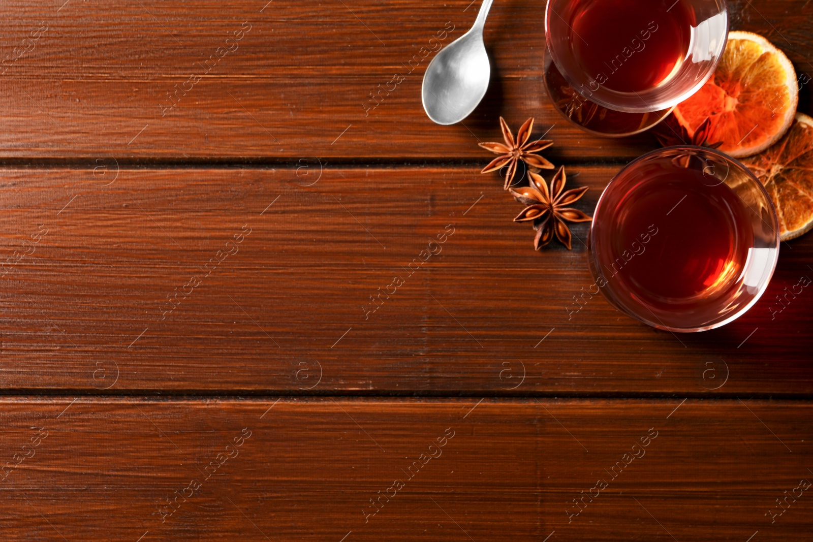 Photo of Glasses of traditional Turkish tea and ingredients on wooden table, flat lay. Space for text
