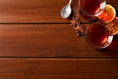 Photo of Glasses of traditional Turkish tea and ingredients on wooden table, flat lay. Space for text