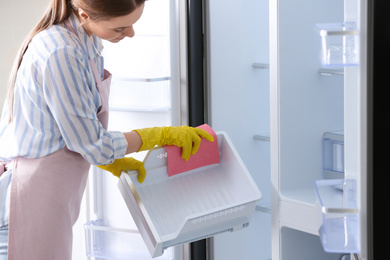 Woman in rubber gloves cleaning refrigerator, closeup