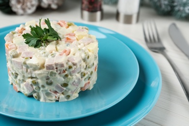 Photo of Traditional russian salad Olivier served on white wooden table, closeup