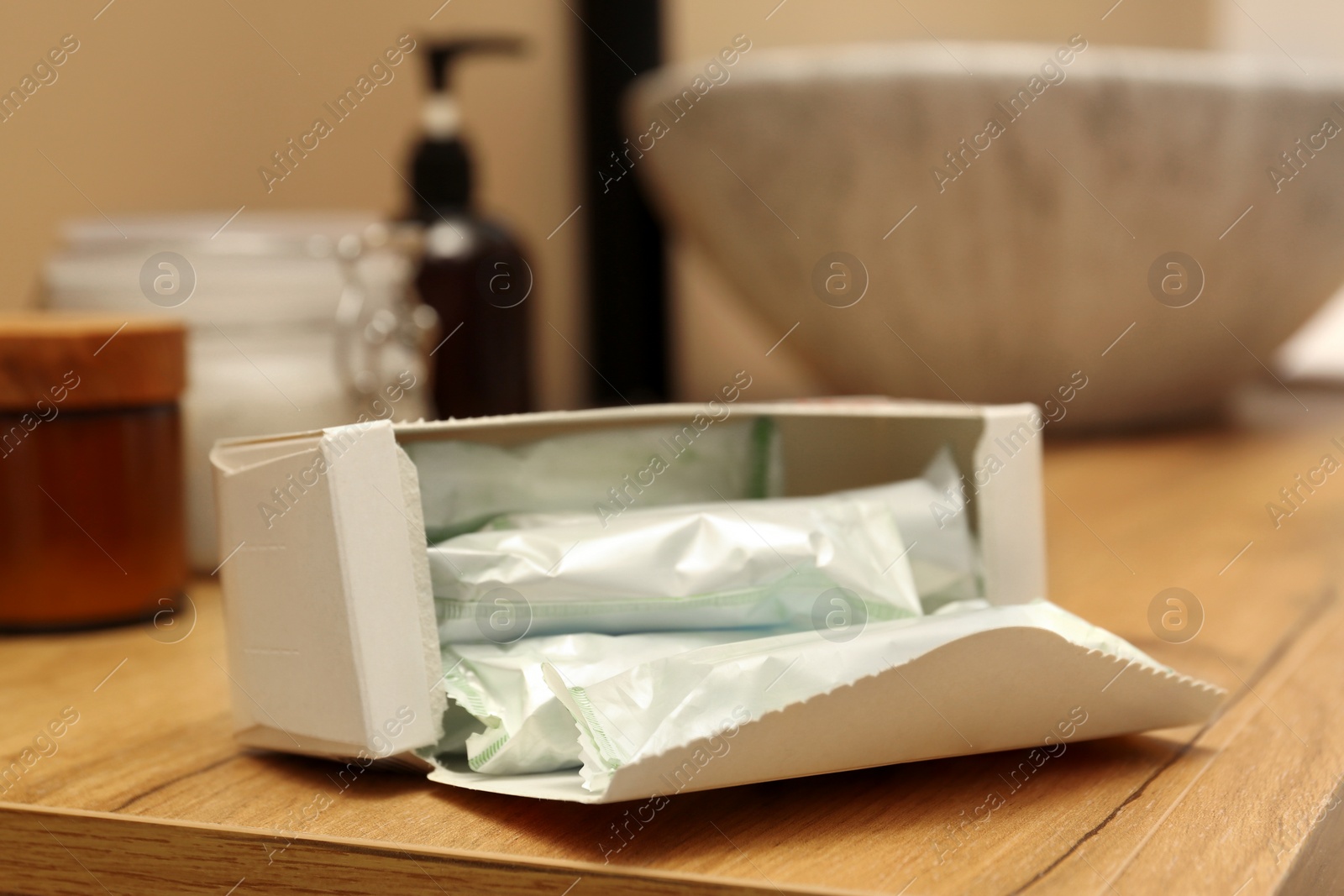 Photo of Package of tampons on wooden countertop in bathroom, closeup. Menstrual hygienic product