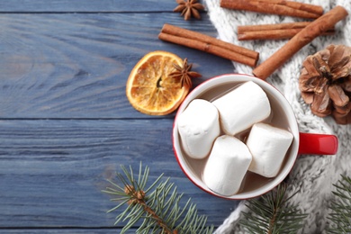 Flat lay composition of tasty cocoa with marshmallows on blue wooden table. Space for text