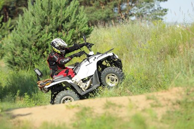 Photo of Man performing trick with modern quad bike on sandy road. Extreme sport