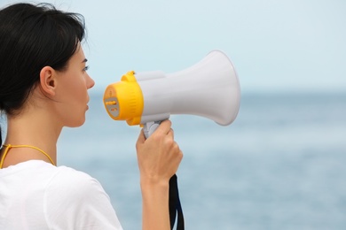 Photo of Beautiful female lifeguard with megaphone near sea