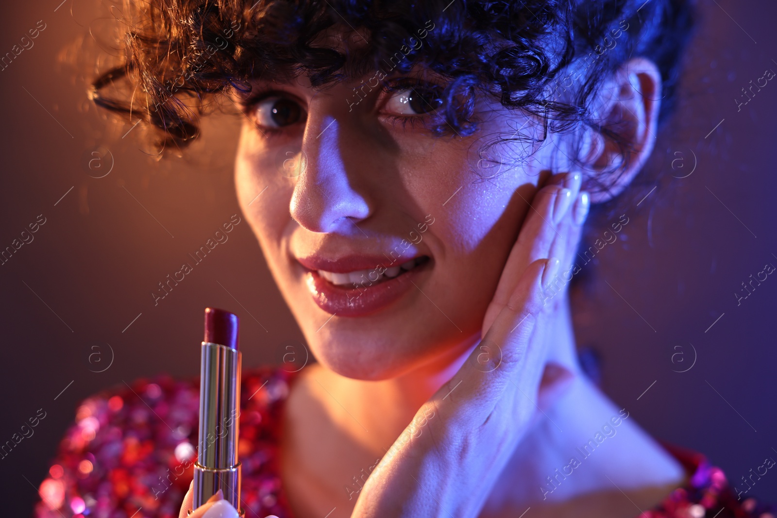 Photo of Beautiful young woman with lipstick posing on color background in neon lights