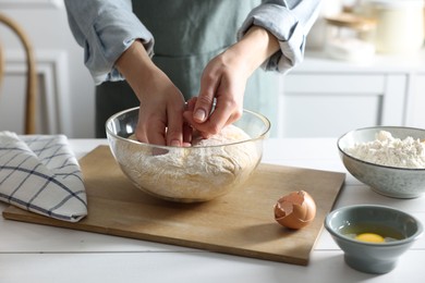 Photo of Woman making dough at white wooden table in kitchen, closeup