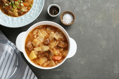 Photo of Tasty cabbage soup with meat and carrot served on grey table, flat lay. Space for text