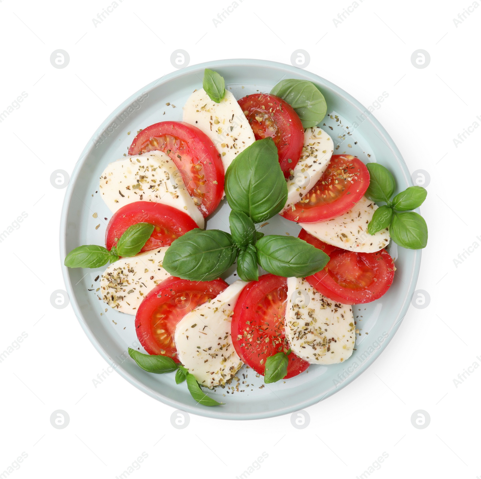 Photo of Plate of delicious Caprese salad with tomatoes, mozzarella, basil and spices isolated on white, top view