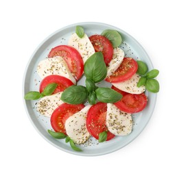 Photo of Plate of delicious Caprese salad with tomatoes, mozzarella, basil and spices isolated on white, top view