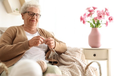 Photo of Elderly woman knitting at home. Creative hobby