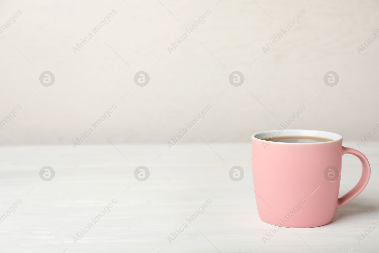 Photo of Pink ceramic cup with hot aromatic coffee on table