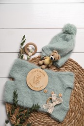 Photo of Children's clothes, toys and green plant on white wooden table, top view