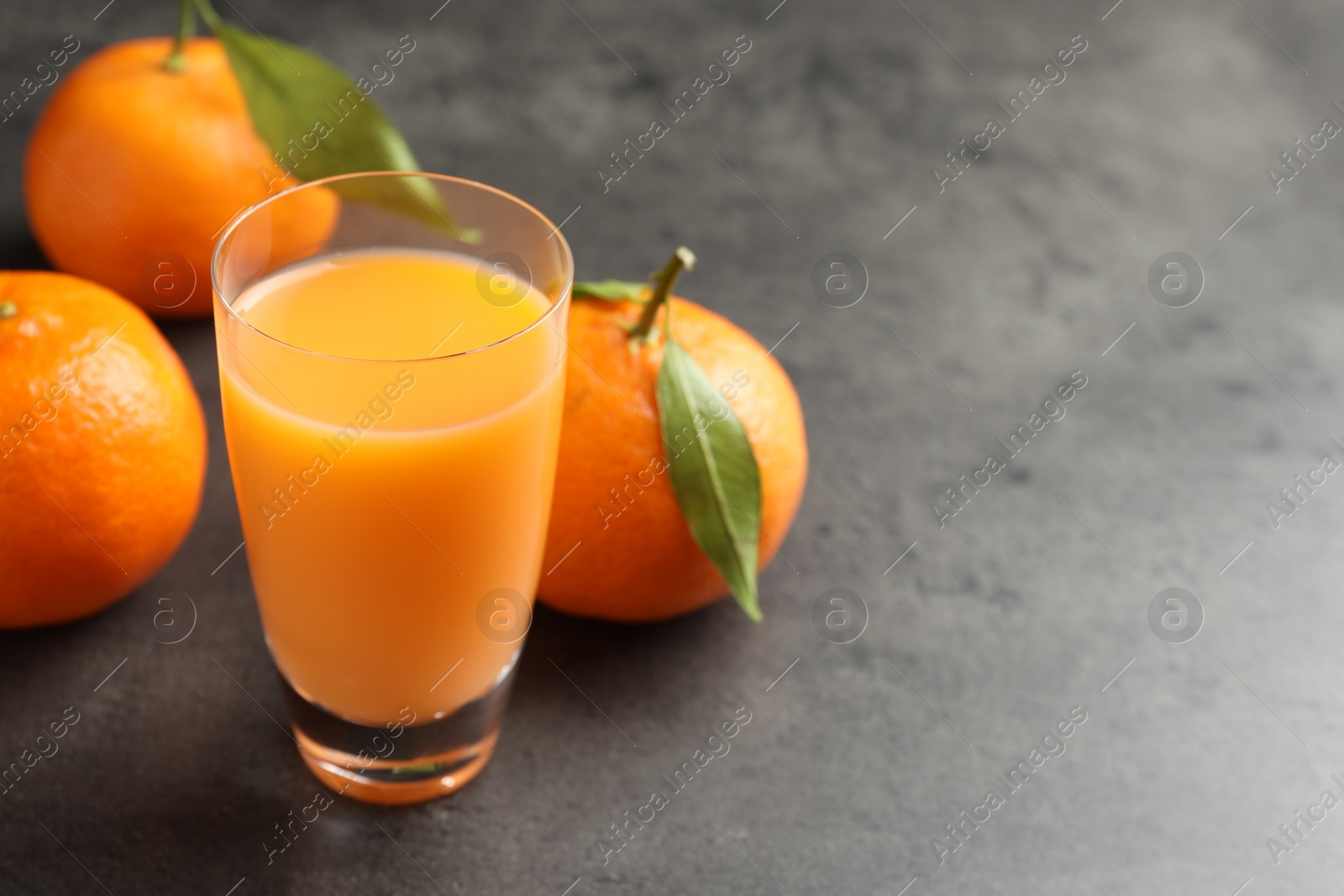 Photo of Delicious tangerine liqueur and fresh fruits on grey table, closeup. Space for text