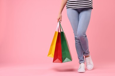 Woman with shopping bags on pink background, closeup. Space for text