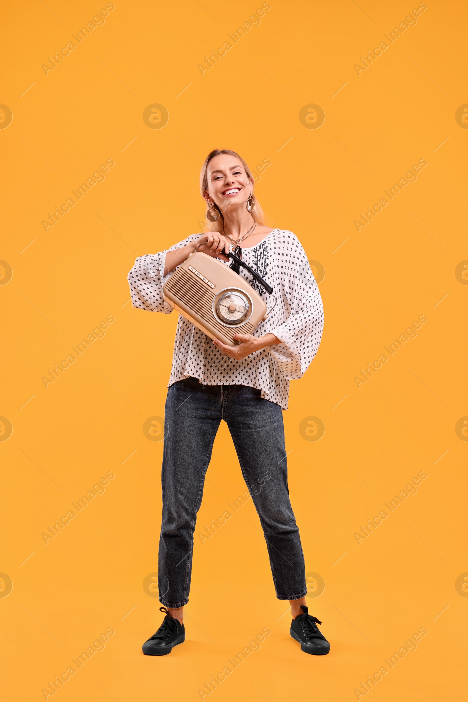 Photo of Portrait of happy hippie woman with retro radio receiver on yellow background