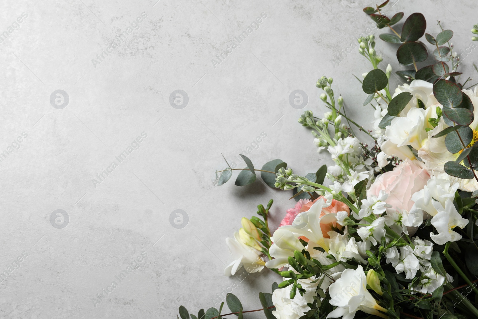 Photo of Bouquet of beautiful flowers on light gray table, top view. Space for text