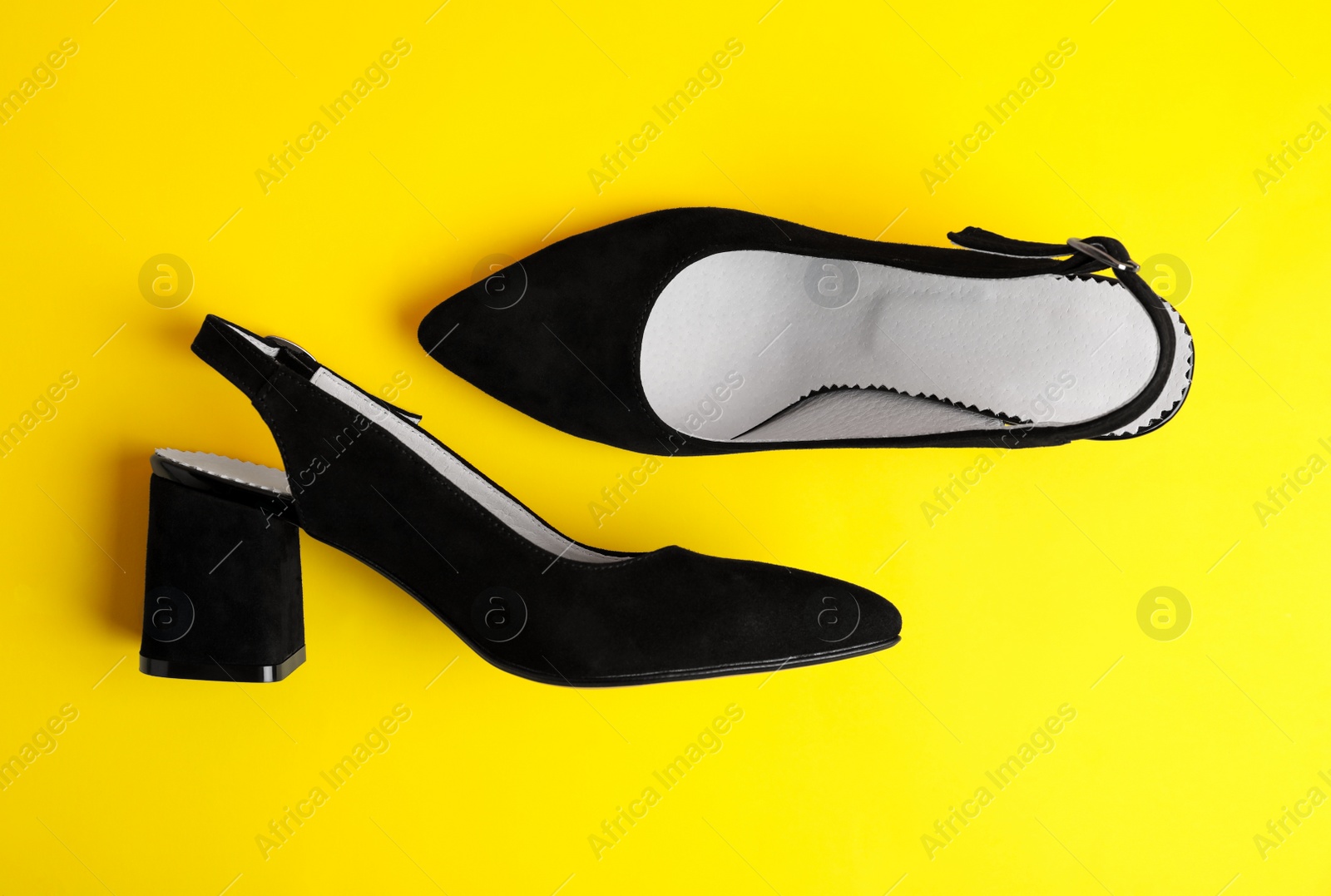 Photo of Stylish female shoes on yellow background, flat lay