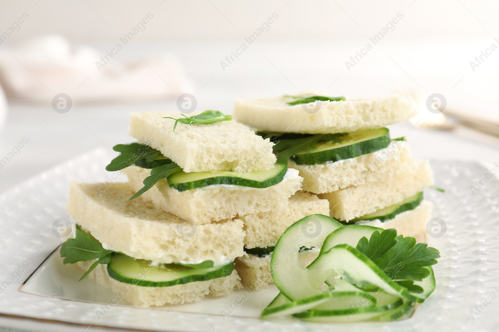 Photo of Tasty cucumber sandwiches with parsley on plate, closeup