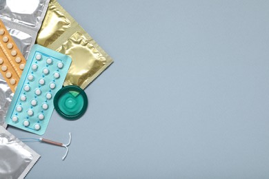 Photo of Contraceptive pills, condoms and intrauterine device on light grey background, flat lay and space for text. Different birth control methods