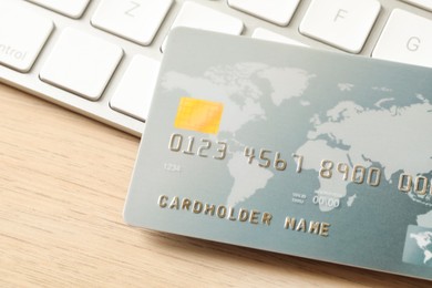 Online payment concept. Bank card and computer keyboard on wooden table, closeup