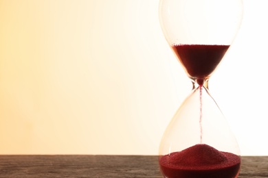 Photo of Hourglass with flowing sand on table against light background. Time management