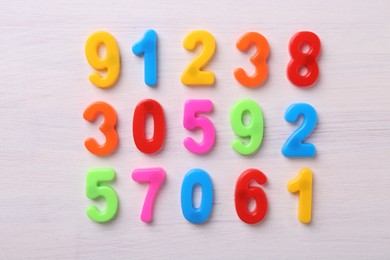 Colorful numbers on white wooden school desk, flat lay