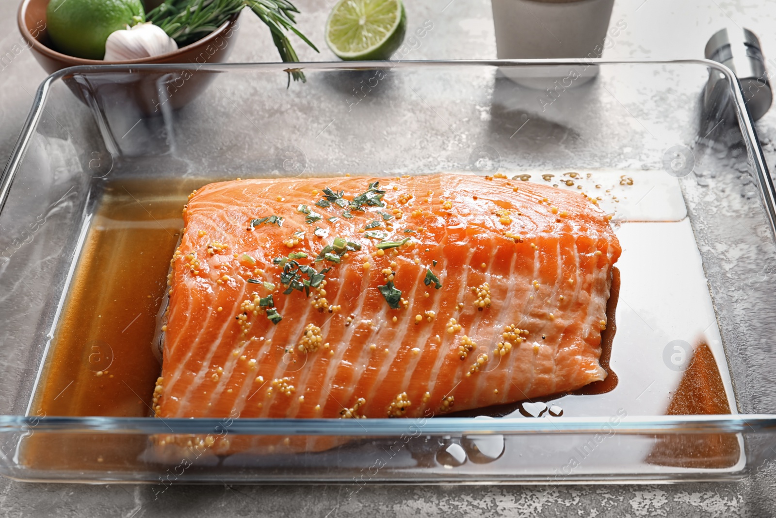 Photo of Raw salmon fillet with marinade in baking dish on table