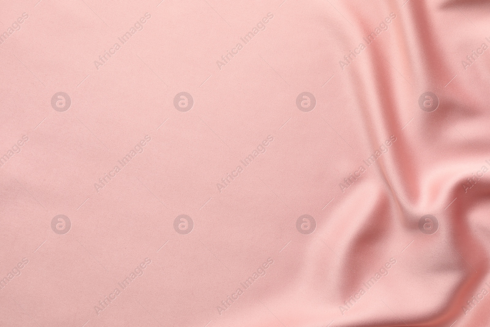 Photo of Crumpled pink silk fabric as background, top view. Space for text