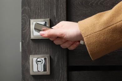 Woman opening wooden door indoors, closeup of hand on handle