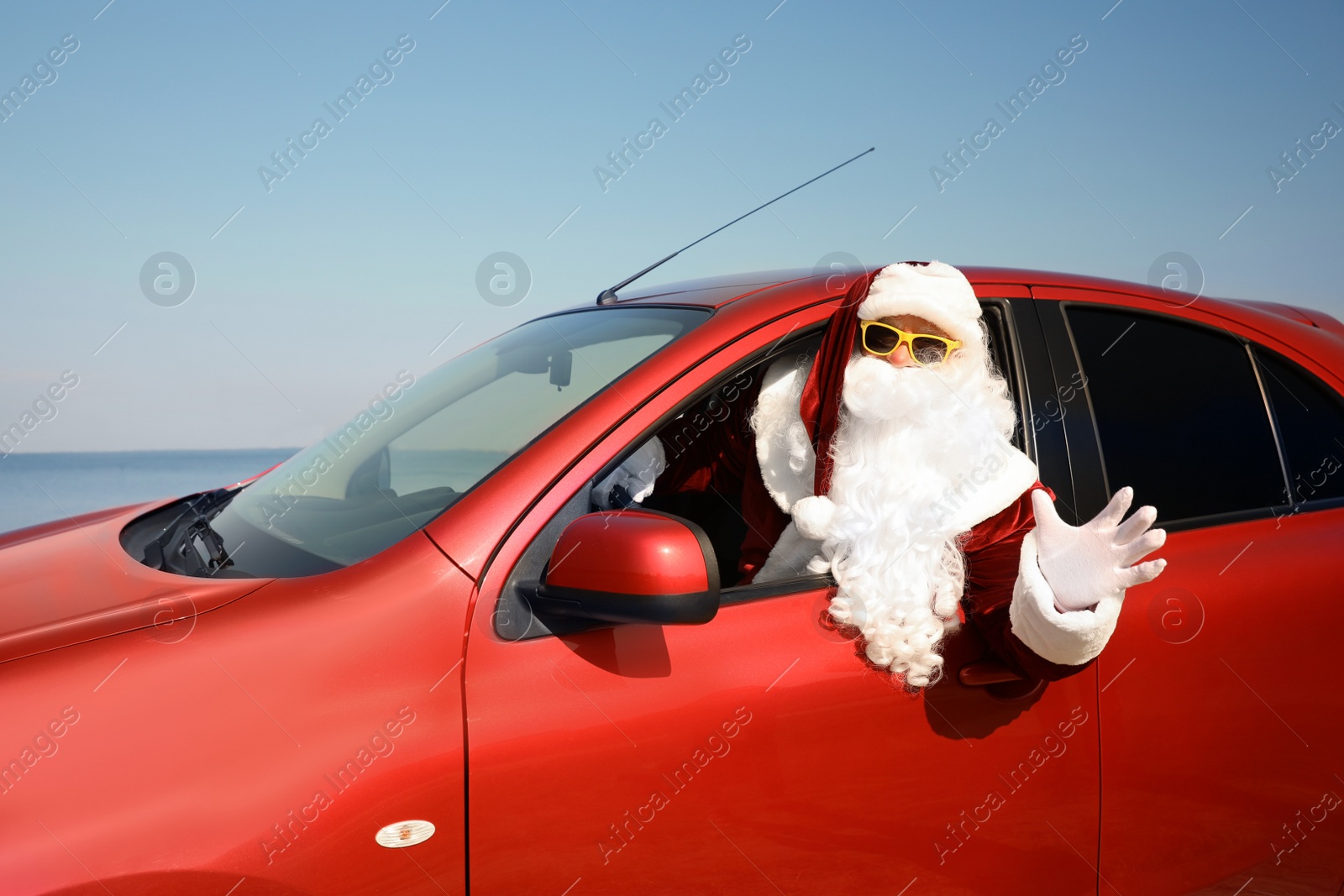 Photo of Authentic Santa Claus driving modern car near sea