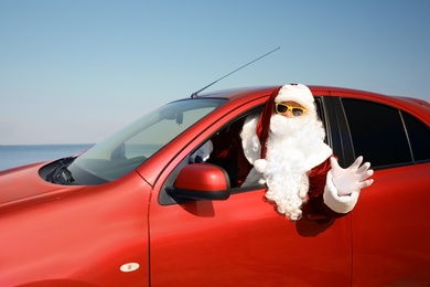 Authentic Santa Claus driving modern car near sea