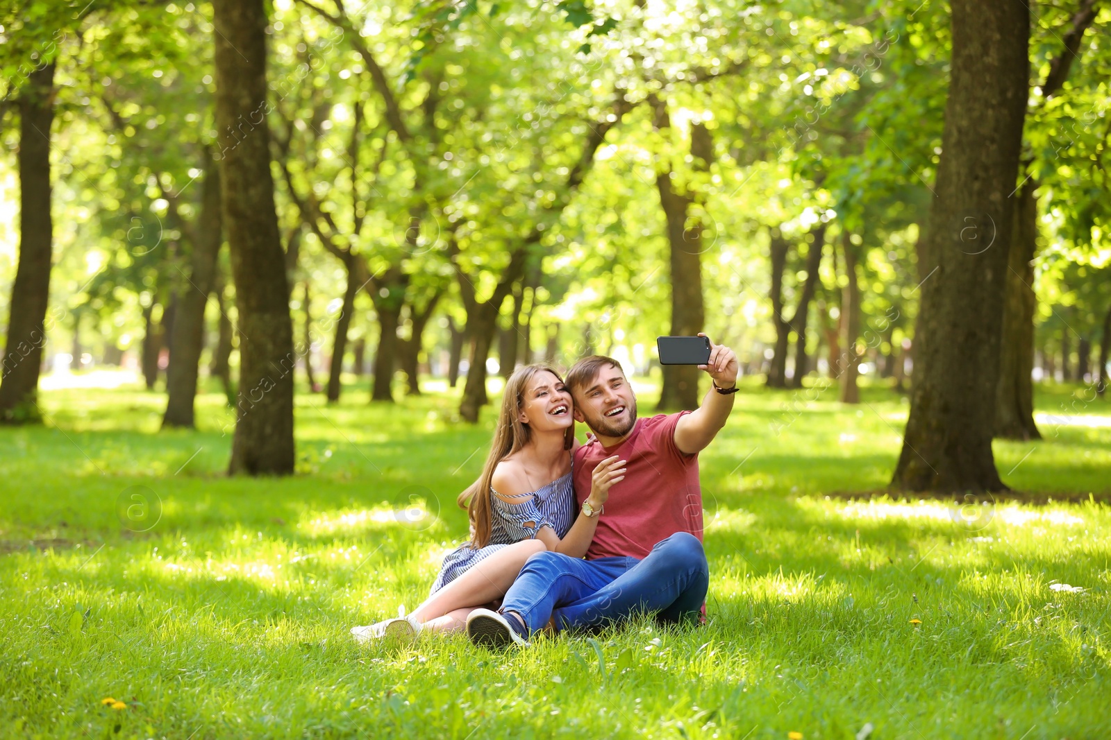 Photo of Happy young couple taking selfie on green grass in park