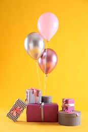 Photo of Many gift boxes and balloons on yellow background