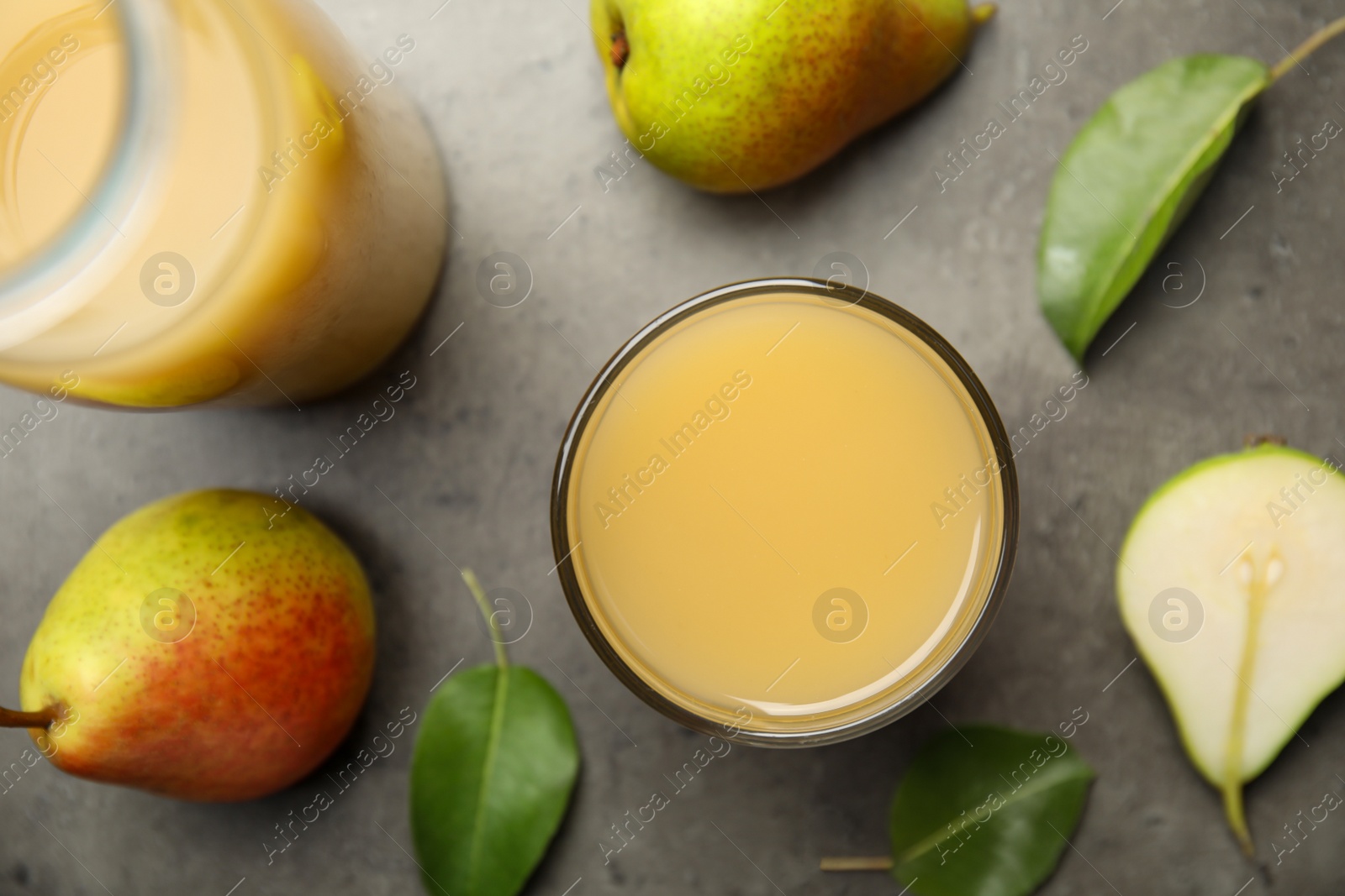 Photo of Tasty pear juice, fruits and leaves on grey table, flat lay