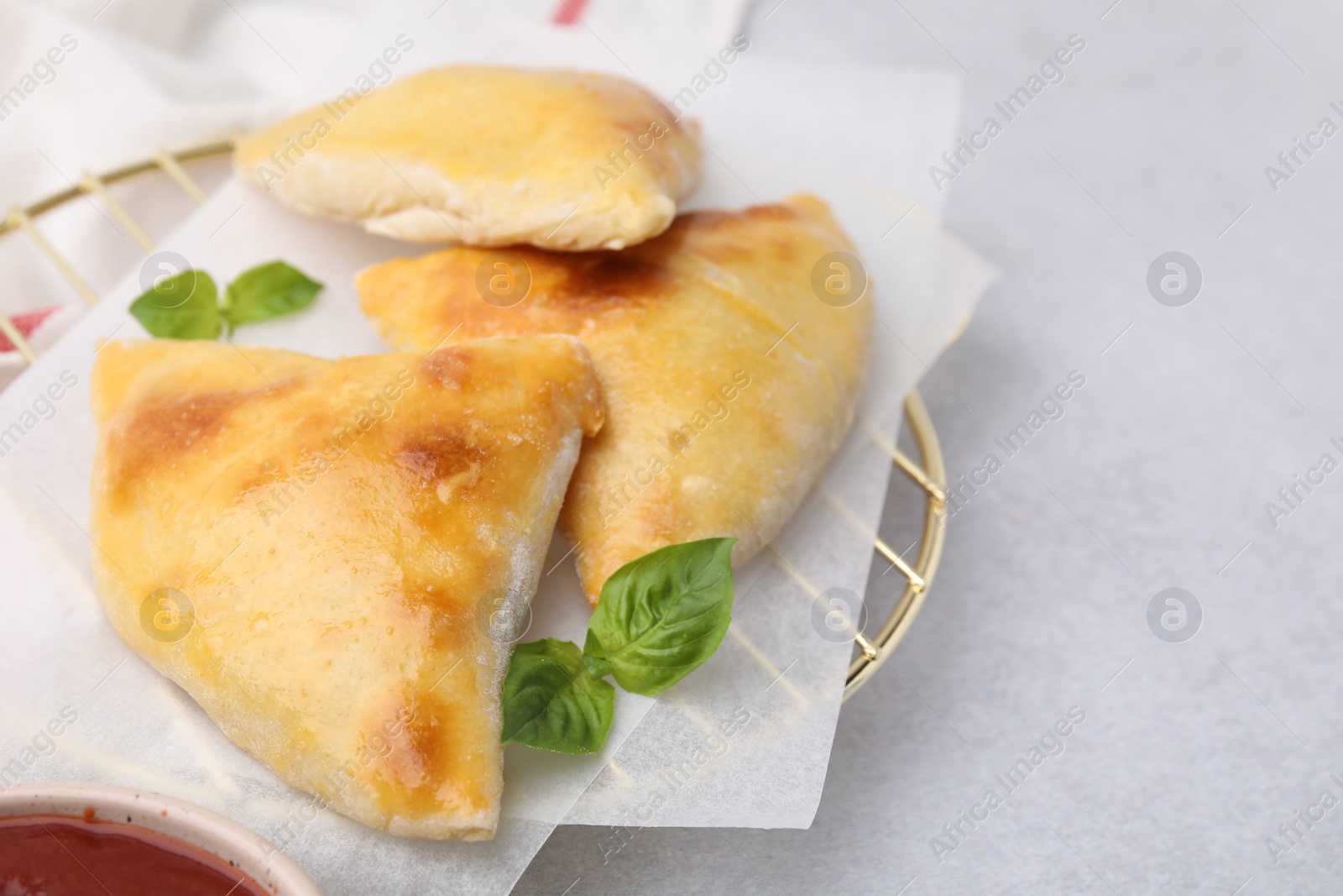 Photo of Delicious samosas and basil on light grey table, space for text