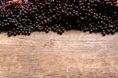 Tasty elderberries (Sambucus) on wooden table, top view. Space for text