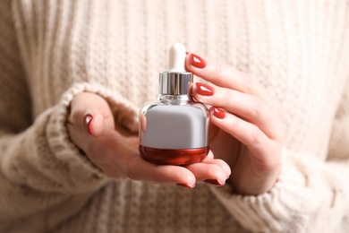 Photo of Woman holding cosmetic product, closeup. Winter care