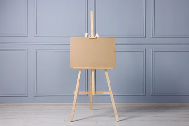 Photo of Wooden easel with blank board near grey wall indoors
