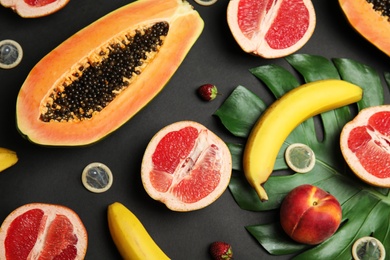 Photo of Flat lay composition with condoms and exotic fruits on black background. Erotic concept