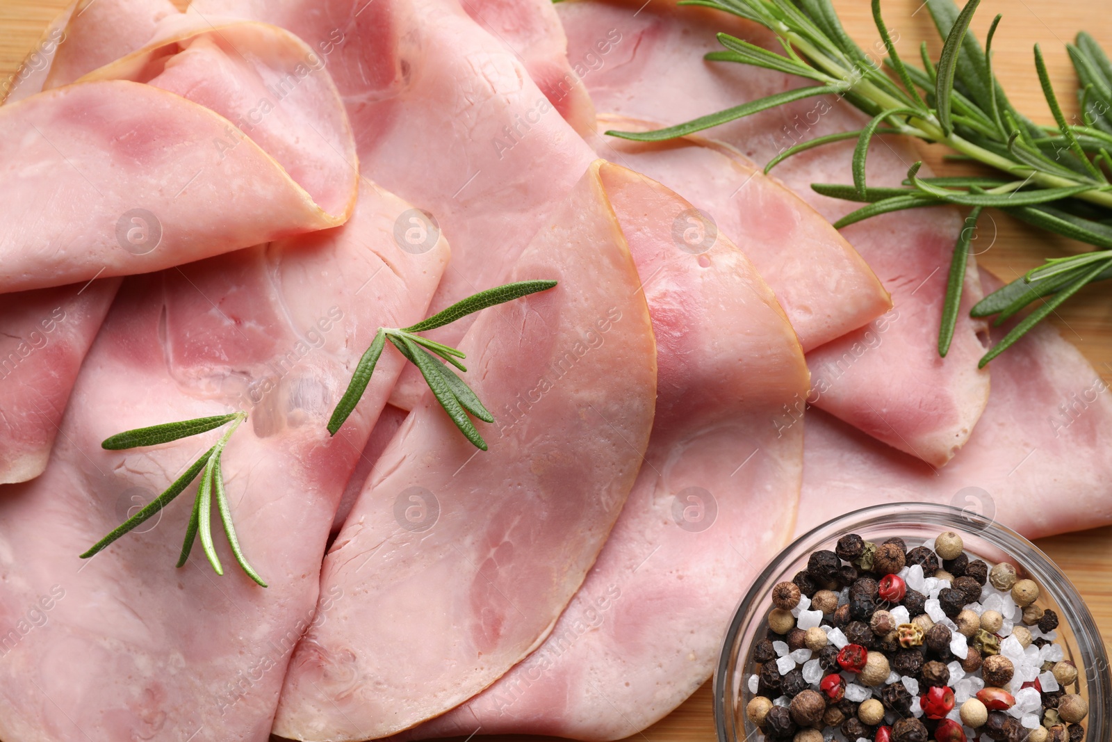 Photo of Slices of delicious ham with rosemary and spices on table, flat lay