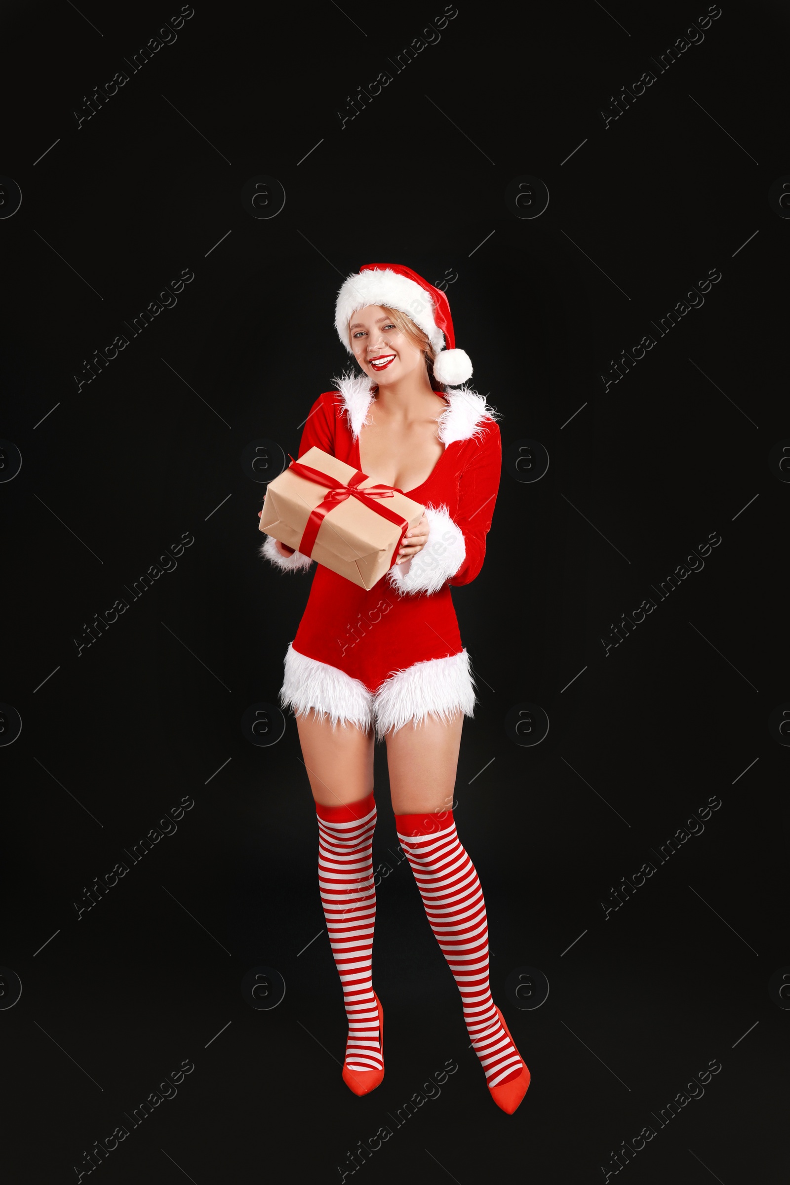 Photo of Beautiful Santa girl with Christmas gift on black background