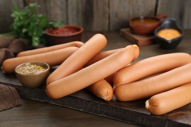 Photo of Delicious sausages and mustard on wooden table