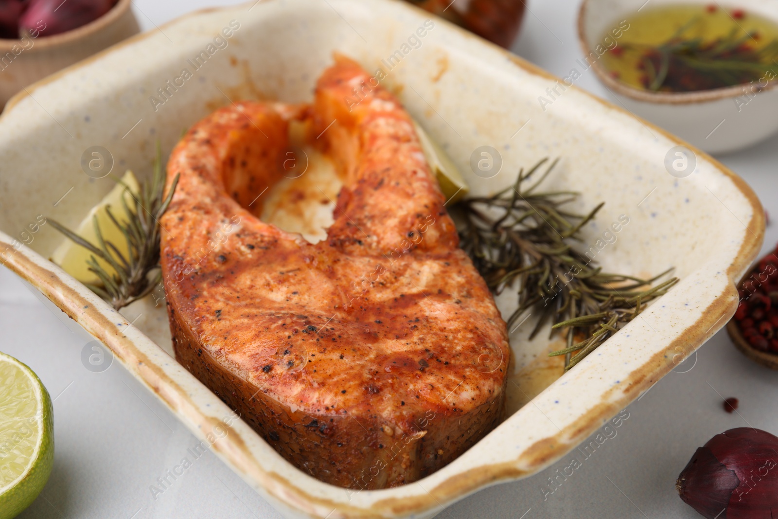 Photo of Freshly cooked fish and other products on white tiled table, closeup