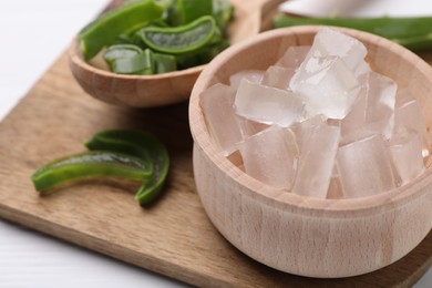 Photo of Aloe vera gel and slices of plant on white table, closeup