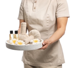 Photo of Professional masseuse in uniform holding tray with spa supplies on white background, closeup