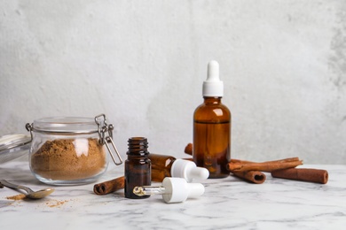 Photo of Composition with cinnamon essential oil and powder on table