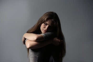 Depressed young woman on gray background