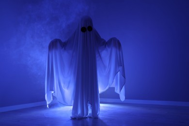Creepy ghost. Woman covered with sheet in blue light